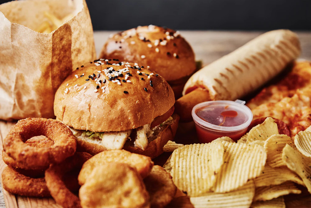 Egészségtelen gyorséttermi ételek, hamburger, nuggets, csipsz és mártogatós.